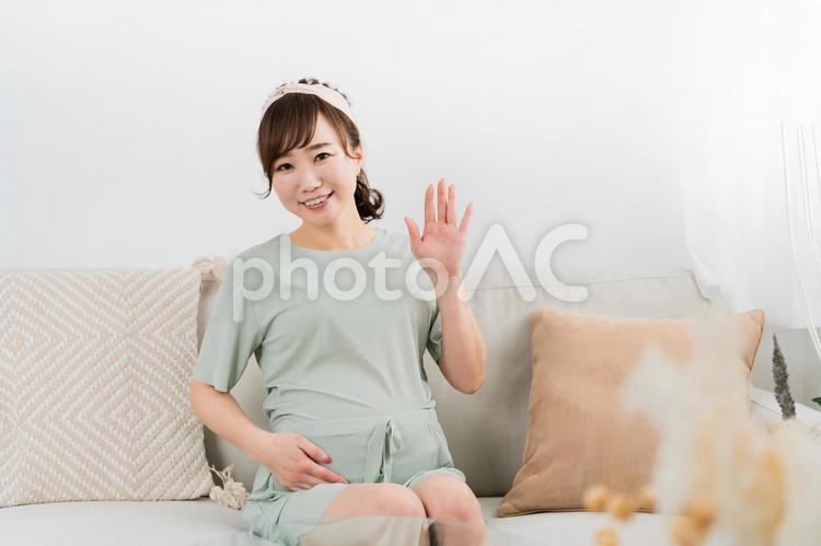 手を振るソファに座る妊婦のアジア人女性 妊婦,妊娠,妊活の写真素材