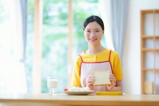 食パンを持ち笑顔の女性 女性,朝食,食事の写真素材