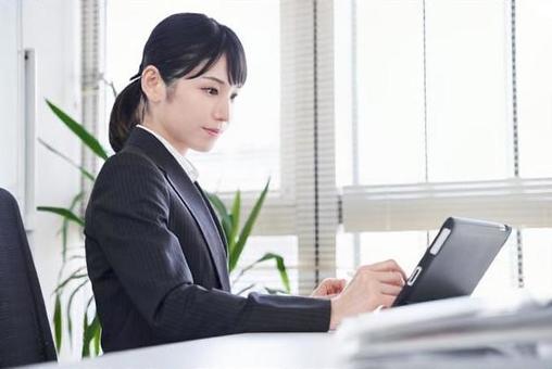 Japanese female business woman who converts paper materials into data using a tablet in the office Japanese female business woman who converts paper materials into data using a tablet in the office