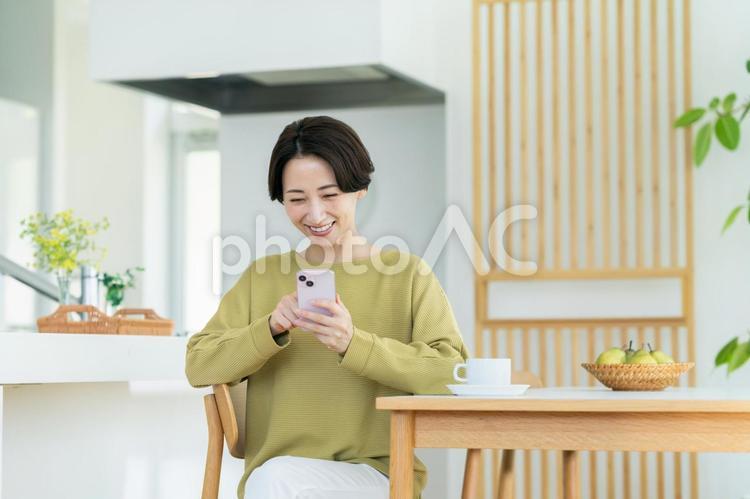 家でスマホを見るミドルの主婦 スマートフォン,女性,主婦の写真素材