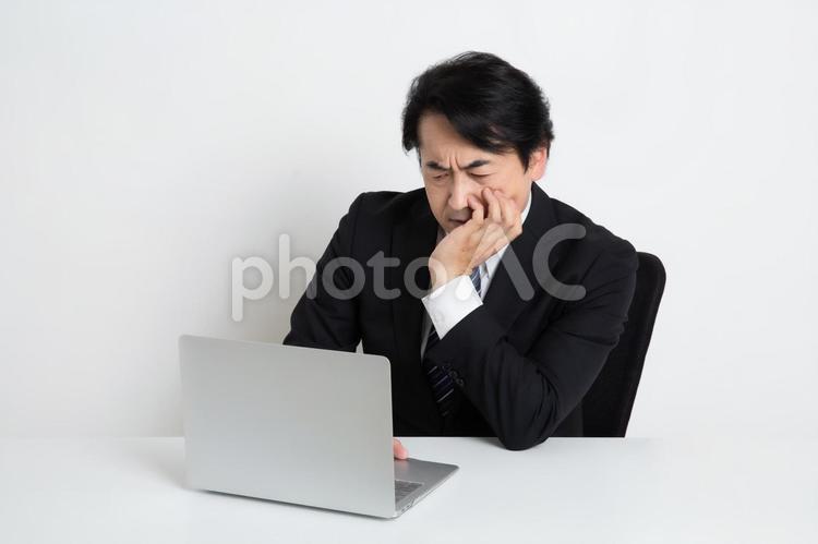 悩みながら仕事をしている中年のサラリーマン男性 中年,上司,会社員の写真素材