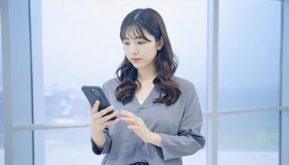 スマホを確認するビジネス女性 スマホを確認するビジネス女性の写真