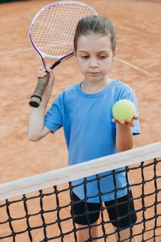 テニスボールを差し出し沈んだ顔の女の子の写真