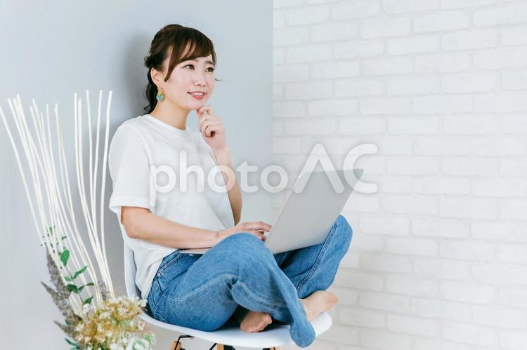 パソコンを使いながら考えるアジア人女性 パソコン,考える,アイディアの写真素材