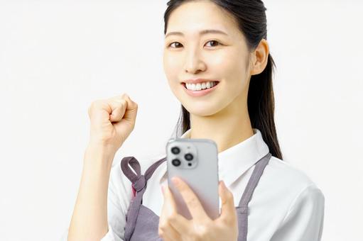 スマホを持ちガッツポーズする主婦 スマホを持ちガッツポーズする主婦 主婦,スマホ,スマートフォンの写真素材