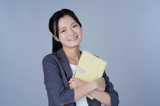 グレーの服の女性が書類を抱える 女性,本,手帳の写真素材