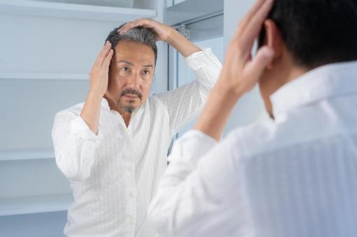 洗面所でヘアケアをするミドルの男性 洗面所でヘアケアをするミドルの男性 ヘアケア,育毛,ヘアセットの写真素材