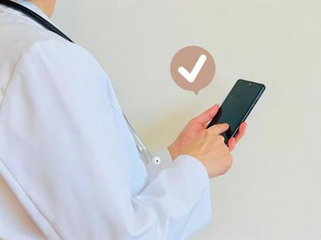 スマホを操作する白衣を着た人 スマホを操作する白衣を着た人 スマホ,女性,チェックの写真素材