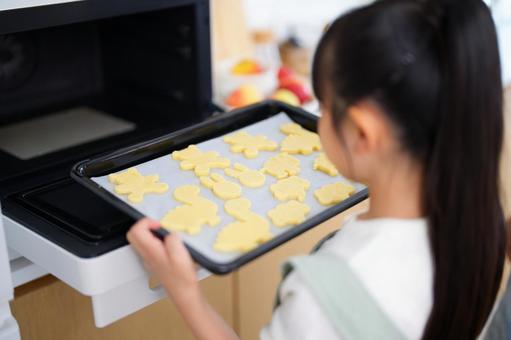 クッキーの天板をオーブンに入れる女の子 女の子,天板,持つの写真素材