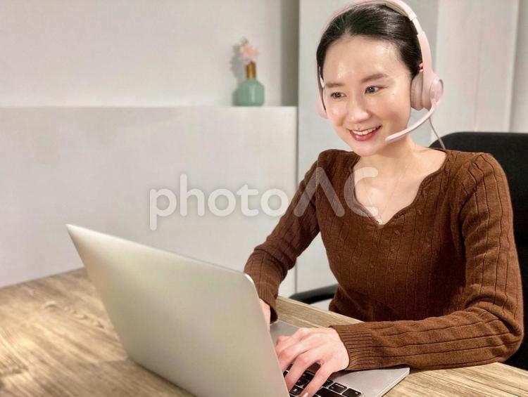 ヘッドフォンをしてリモート会議をする女性 女性,笑顔,リモート会議の写真素材