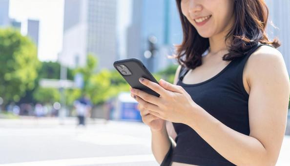 スマートフォンを操作する若い女性 スマートフォンを操作する若い女性の写真