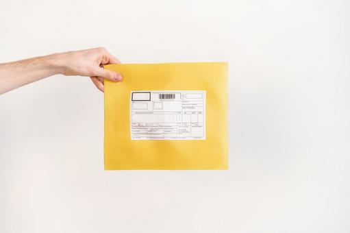 宛名ラベルの貼られたクッション封筒を持つ手 配達,デリバリー,郵便の写真素材