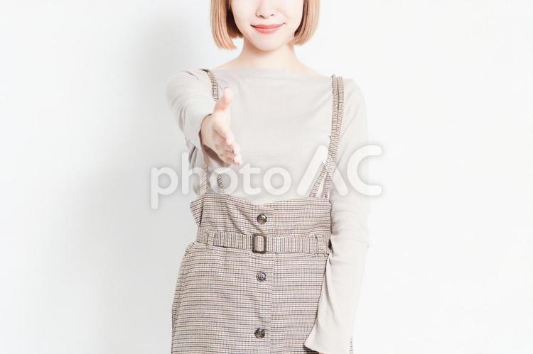白い壁の前に立って、手を差し出す若い女の子 手,差し出す,腕の写真素材