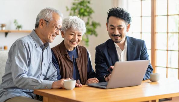ビジネスマンが持つ画面を見るシニア夫婦 ビジネスマンが持つ画面を見るシニア夫婦の写真