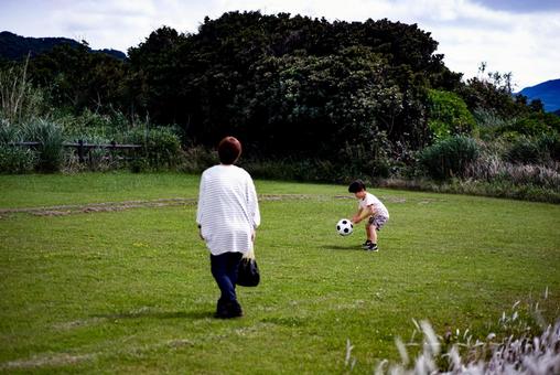 <素材>芝生の公園でサッカーをする親子 <素材>芝生の公園でサッカーをする親子 女性,子供,男性の写真素材