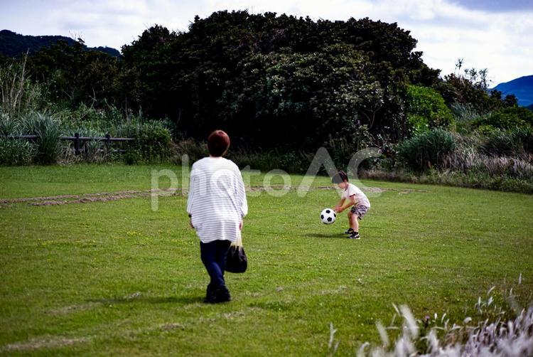※＜素材＞芝生の公園でサッカーをする親子 女性,子供,男性の写真素材
