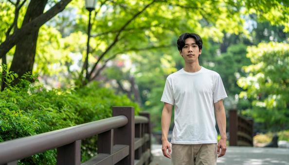 都会の公園を散歩する私服姿の若い男性 都会の公園を散歩する私服姿の若い男性の写真