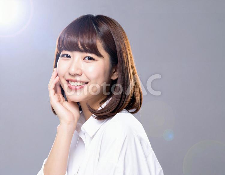 頬に手を当てて微笑む女性 女性,笑顔,セミロングの写真素材