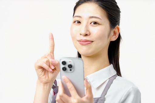 スマホを持ち説明する主婦 エプロンの女性 スマホを持ち説明する主婦 エプロンの女性 主婦,スマホ,スマートフォンの写真素材