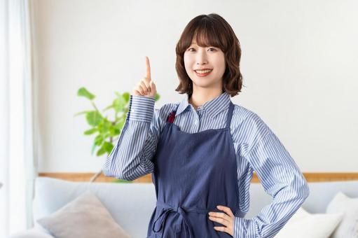 A woman in an apron pointing with her index finger, JPG