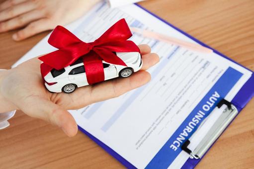 リボンを巻いた車の模型と書類 人物,手元,ボディパーツの写真素材