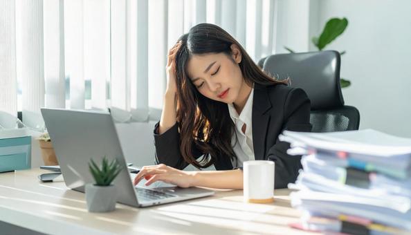 デスクで頭を抱えているビジネスマン デスクで頭を抱えているビジネスマンの写真