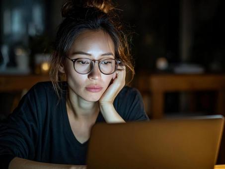 深夜に一人で調べものをする女性の写真