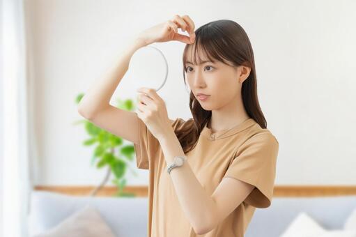 鏡を見て髪をチェックをする女性 女性,髪,髪の毛の写真素材