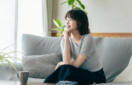リビングのソファに座る笑顔の女性 リビングのソファに座る笑顔の女性 女性,ソファ,微笑むの写真素材