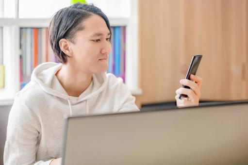 笑顔でスマホを見る男性 笑顔でスマホを見る男性の写真