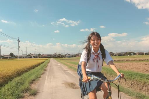 田んぼのあぜ道を自転車で走る女子高生 田んぼのあぜ道を自転車で走る女子高生の写真