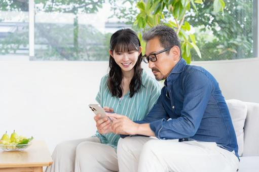 リビングでスマホを見るミドルの夫婦 夫婦,家族,ミドルの写真素材
