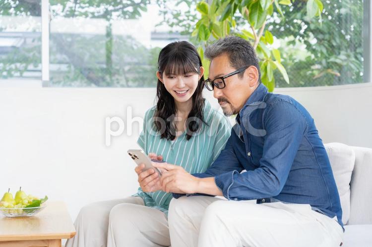 リビングでスマホを見るミドルの夫婦 夫婦,家族,ミドルの写真素材