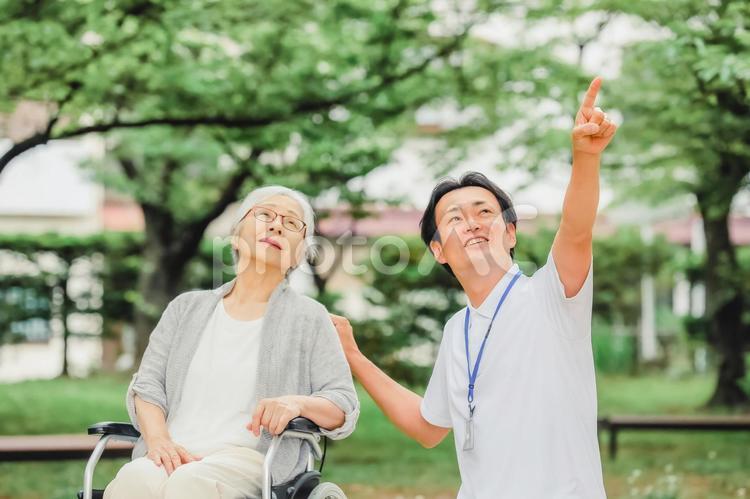 車椅子に乗った高齢者女性と男性スタッフ 介護士,看護師,理学療法士の写真素材