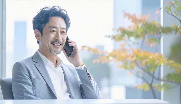 笑顔で電話する中年 笑顔で電話する中年の写真