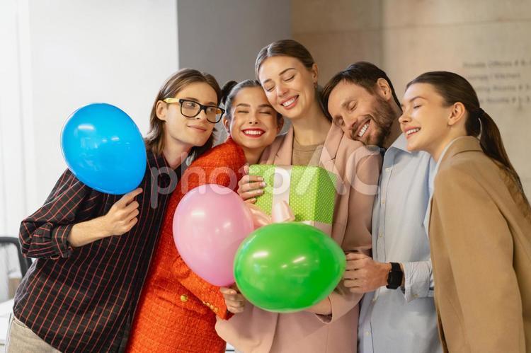 オフィスで女性の誕生日を祝って寄り添って写真撮影する同僚たち ビジネス,ビジネスマン,ビジネスウーマンの写真素材