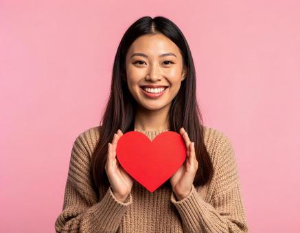 ハートを手に優しく微笑む女性 ハートを手に優しく微笑む女性の写真