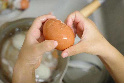 ゆで卵の殻をむく子どもの手の写真