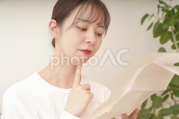 書類を見て複雑な表情をする女性 請求書,催告書,督促状の写真素材