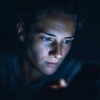 画面の光に照らされた集中した表情 画面の光に照らされた集中した表情の写真