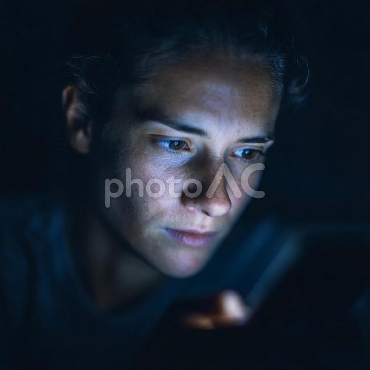 画面の光に照らされた集中した表情 スマートフォン,画面,暗闇の写真素材
