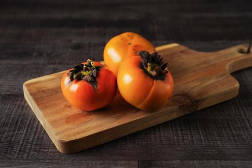 カッティングボードに置かれた柿 カッティングボードに置かれた柿 柿,果物,かきの写真素材