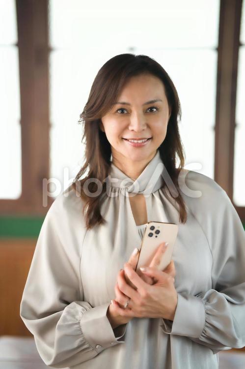 カメラ目線で携帯を持っている女性 女性,主婦,携帯の写真素材