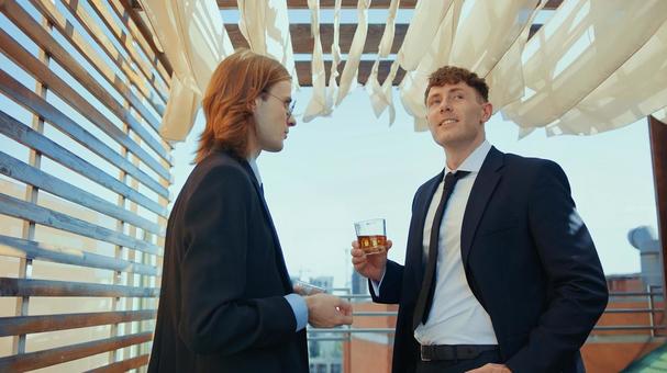 グラスを持ち振り向く男性を見る長髪の男性 男性,外国人,笑顔の写真素材