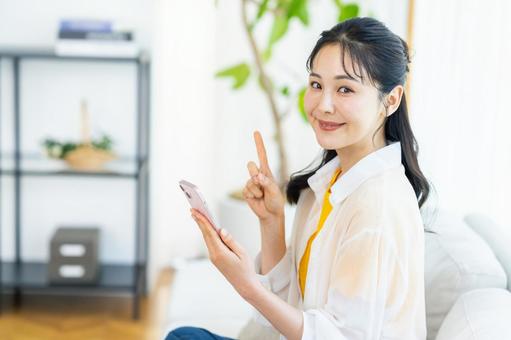 部屋でスマホを操作する女性 スマホ,笑顔,部屋の写真素材