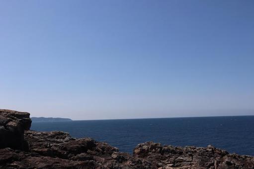 断崖と青い海と半島と水平線と空の風景の写真
