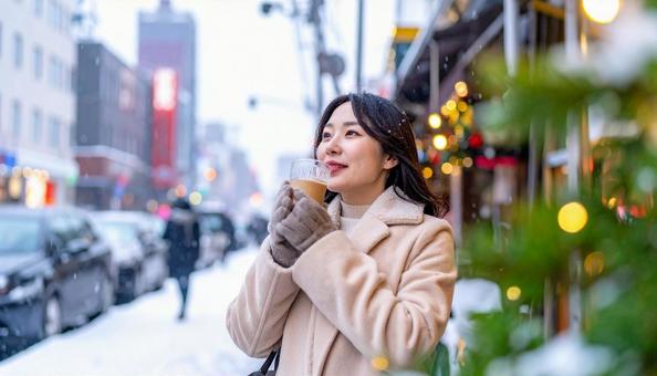 雪の降る冬の街角で飲み物を飲む日本人女性 雪の降る冬の街角で飲み物を飲む日本人女性の写真