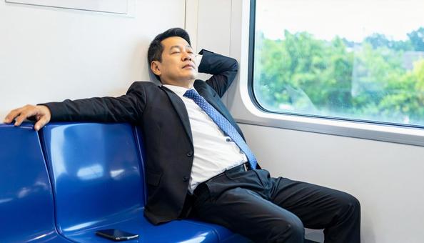 電車内で寝る中年男性 電車内で寝る中年男性の写真