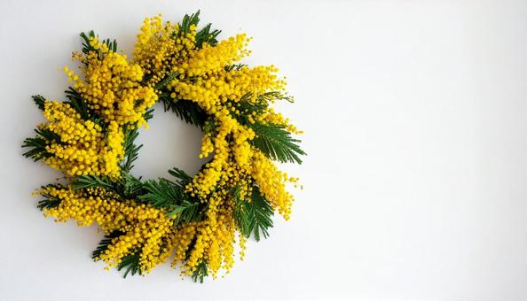 白い壁に飾られたミモザのリースの写真