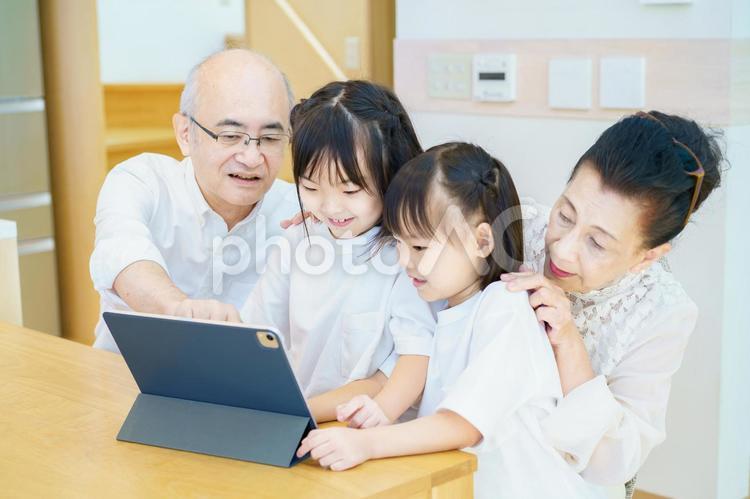タブレットPCを操作する老夫婦と孫たち  シニア夫婦,部屋,インテリアの写真素材